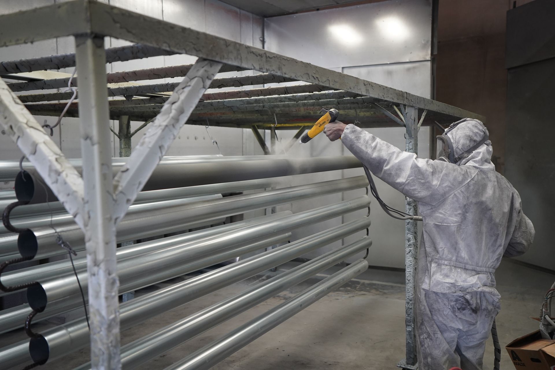 Tecnico che applica una verniciatura a polvere industriale in cabina